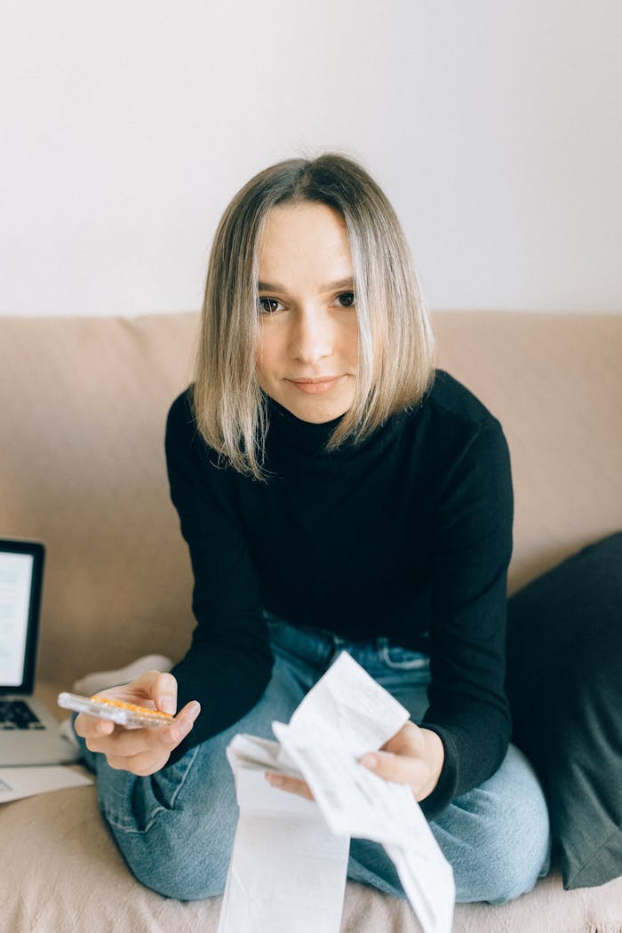 Young woman in black turtleneck managing finances with receipts and calculator at home.